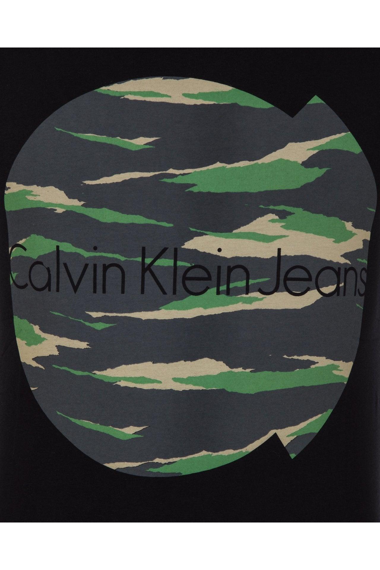 Black fabric with Calvin Klein Jeans logo over green and beige camo pattern in circular design